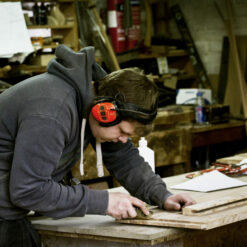 An employee wearing ear defenders while working