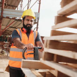 Employee pushing stack of pallets through a warehouse